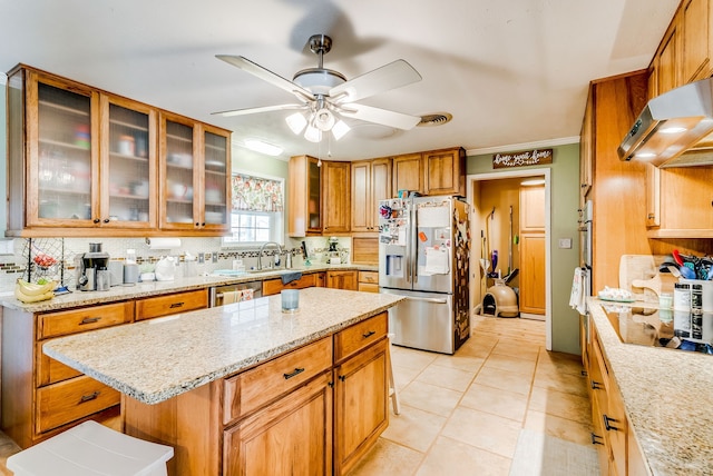 kitchen featuring ceiling fan, a center island, a kitchen breakfast bar, decorative backsplash, and appliances with stainless steel finishes