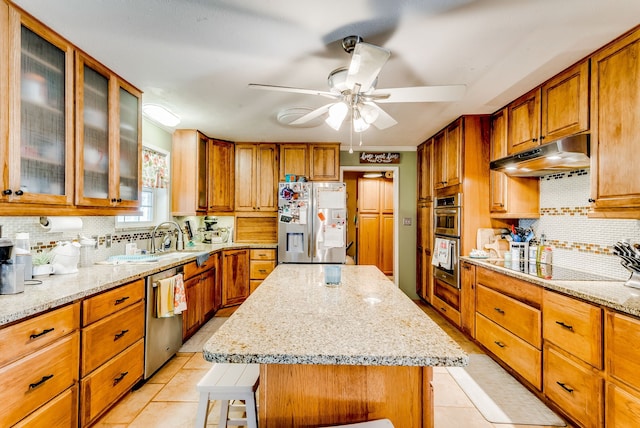 kitchen with decorative backsplash, light stone countertops, a breakfast bar, stainless steel appliances, and a center island