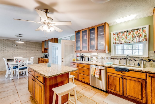 kitchen with light stone countertops, dishwasher, a kitchen island, and sink