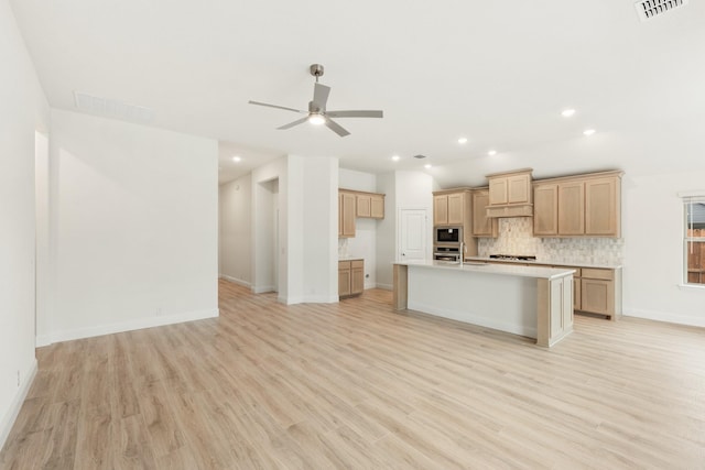 kitchen with ceiling fan, sink, stainless steel appliances, light hardwood / wood-style flooring, and an island with sink