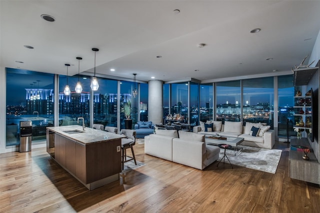 living room with floor to ceiling windows, sink, and light hardwood / wood-style floors