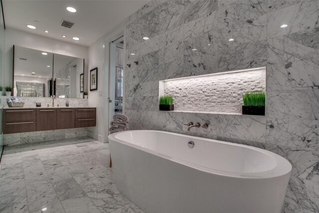 bathroom with vanity, a bathtub, and tile walls