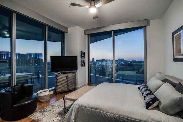 bedroom featuring access to outside, ceiling fan, expansive windows, and wood-type flooring