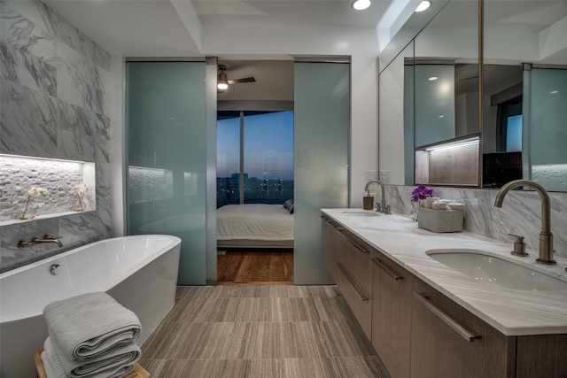 bathroom with vanity, ceiling fan, a tub, and tile walls