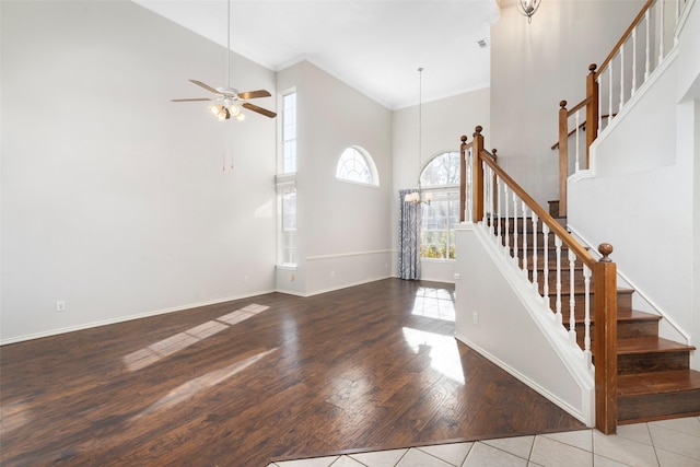 entrance foyer featuring ceiling fan with notable chandelier, ornamental molding, a high ceiling, and light wood-type flooring