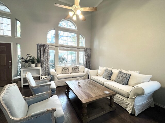 living room with a towering ceiling, dark wood-type flooring, and ceiling fan