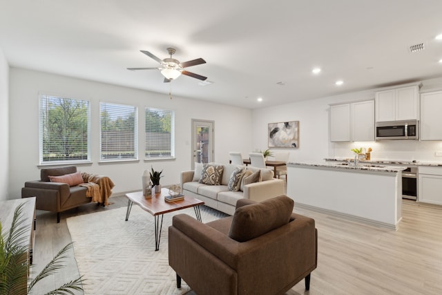 living room featuring ceiling fan and light hardwood / wood-style floors