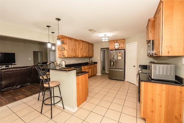 kitchen featuring kitchen peninsula, pendant lighting, a breakfast bar, appliances with stainless steel finishes, and light wood-type flooring