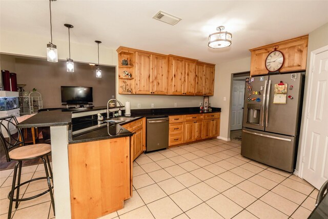 kitchen with kitchen peninsula, a breakfast bar, stainless steel appliances, sink, and hanging light fixtures