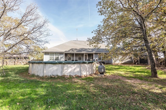 back of property featuring a yard and a covered pool