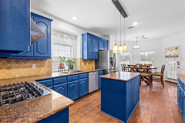 kitchen with sink, blue cabinetry, stainless steel appliances, a center island, and decorative light fixtures