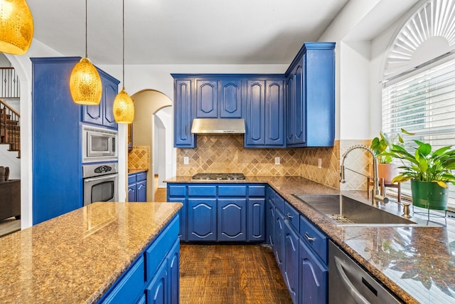 kitchen featuring sink, appliances with stainless steel finishes, dark stone countertops, blue cabinets, and decorative light fixtures