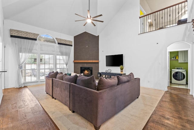 living room with high vaulted ceiling, washer / dryer, light hardwood / wood-style floors, and ceiling fan