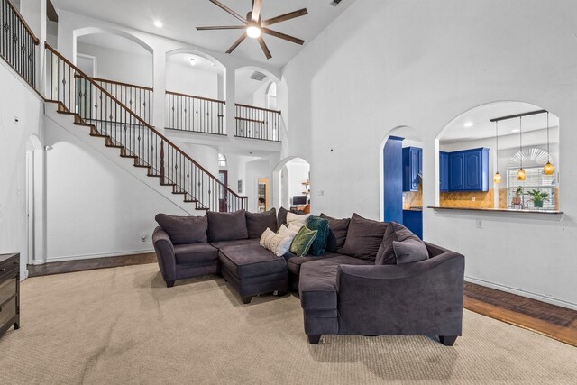 carpeted living room featuring ceiling fan, a large fireplace, high vaulted ceiling, and washer / dryer