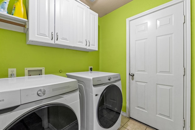 washroom featuring light tile patterned floors, cabinets, and washing machine and clothes dryer