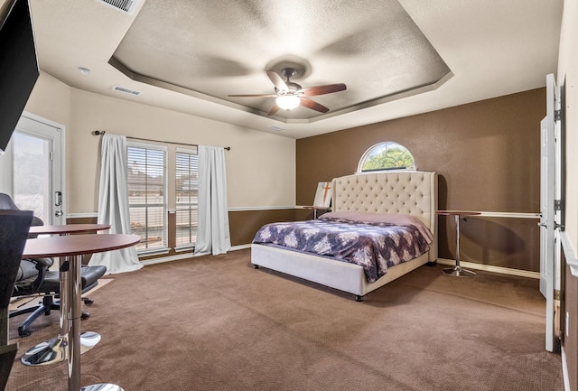 carpeted bedroom featuring a raised ceiling and multiple windows