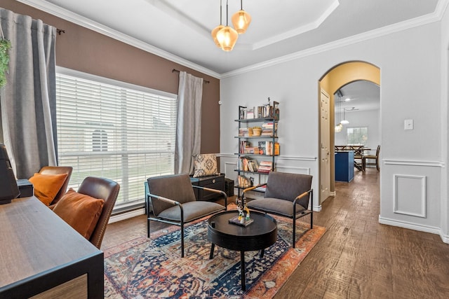 living area with a tray ceiling, dark wood-type flooring, and ornamental molding