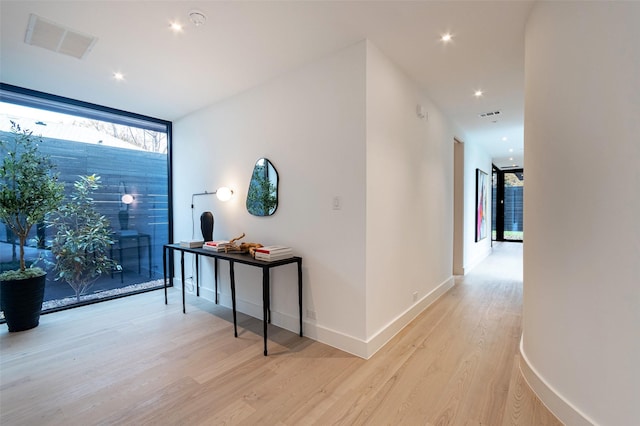 hall with floor to ceiling windows and light wood-type flooring