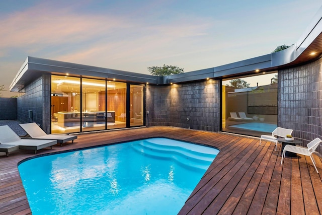 pool at dusk featuring a deck