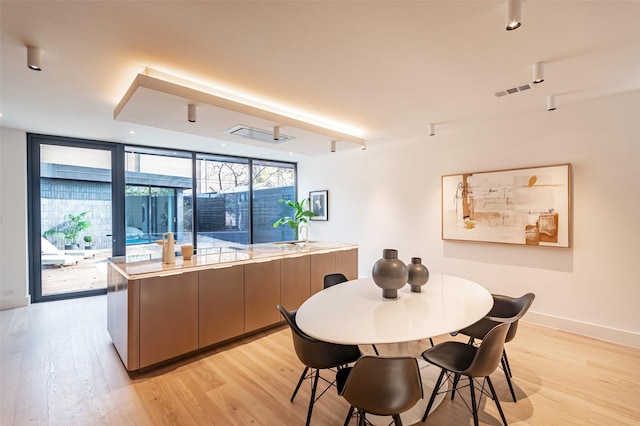 dining space with light hardwood / wood-style flooring and a wall of windows