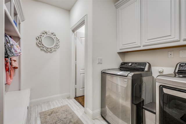 laundry area with washer and clothes dryer, light hardwood / wood-style floors, and cabinets