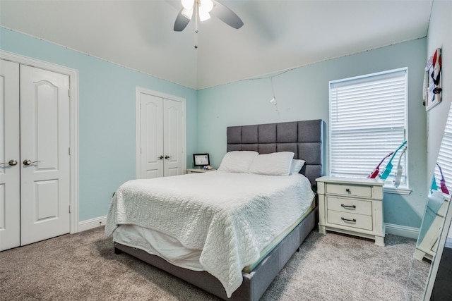 bedroom with ceiling fan, light colored carpet, and multiple closets