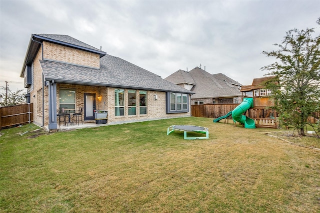 rear view of house with a playground, a patio area, and a lawn