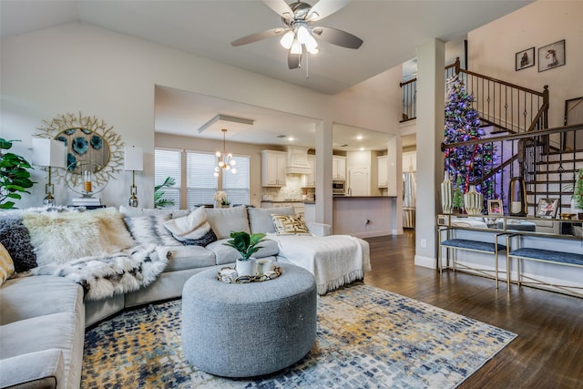 living room with lofted ceiling, ceiling fan with notable chandelier, and dark wood-type flooring