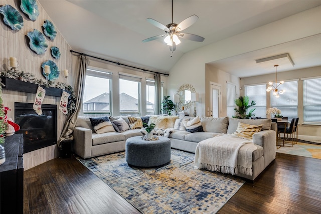 living room featuring ceiling fan with notable chandelier, lofted ceiling, and dark wood-type flooring