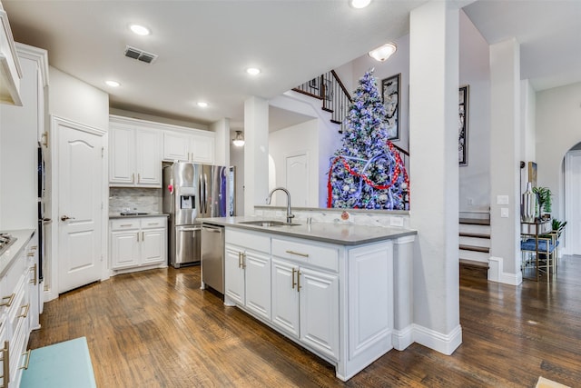 kitchen with white cabinetry, sink, stainless steel appliances, dark wood-type flooring, and decorative backsplash