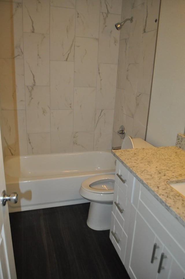 full bathroom with hardwood / wood-style flooring, tiled shower / bath, vanity, and toilet