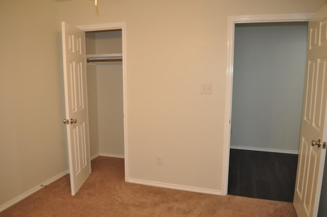 unfurnished bedroom with a closet and light colored carpet