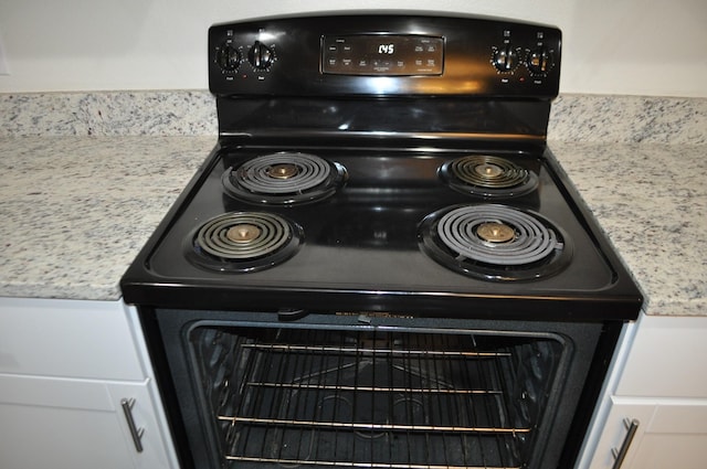 details featuring white cabinets, black range with electric stovetop, and light stone countertops