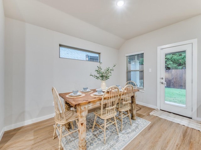 dining room with light wood-type flooring and vaulted ceiling