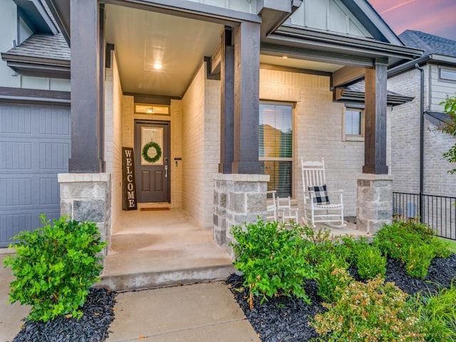 exterior entry at dusk with covered porch and a garage