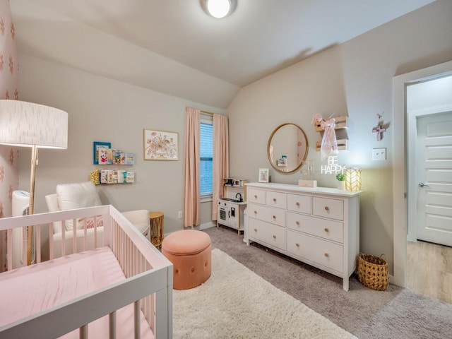 carpeted bedroom featuring lofted ceiling and a crib