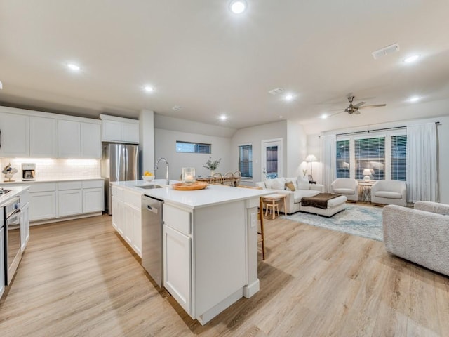 kitchen with backsplash, a center island with sink, sink, appliances with stainless steel finishes, and white cabinets