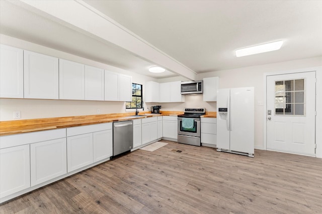 kitchen with butcher block counters, white cabinets, light hardwood / wood-style floors, and appliances with stainless steel finishes