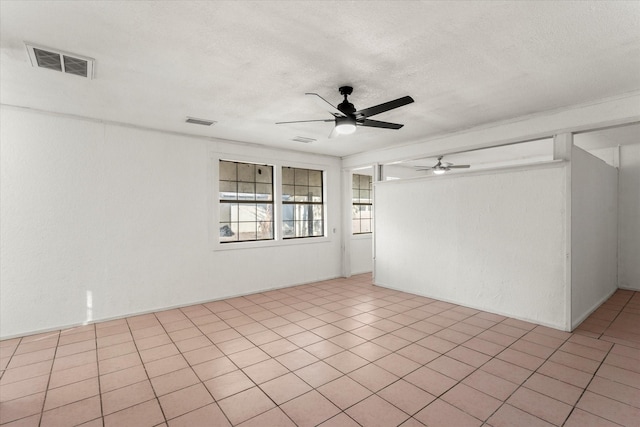 tiled empty room with ceiling fan and a textured ceiling