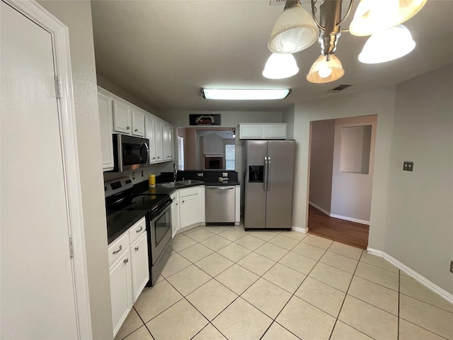 kitchen featuring white cabinetry, sink, light tile patterned floors, and stainless steel appliances