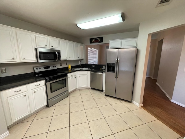 kitchen with sink, white cabinets, light wood-type flooring, and appliances with stainless steel finishes