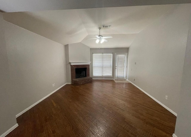 unfurnished living room featuring vaulted ceiling, ceiling fan, dark hardwood / wood-style floors, and a brick fireplace