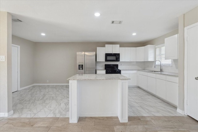 kitchen featuring white cabinetry, a center island, sink, light stone counters, and black appliances