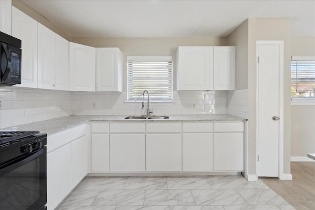 kitchen with white cabinetry, sink, light stone countertops, tasteful backsplash, and black appliances