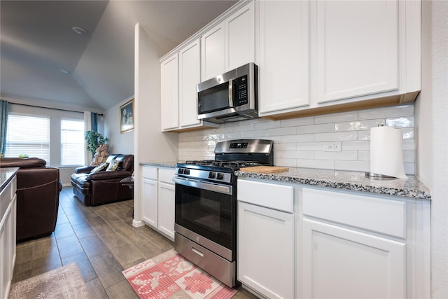 kitchen featuring white cabinetry, light hardwood / wood-style floors, lofted ceiling, and appliances with stainless steel finishes