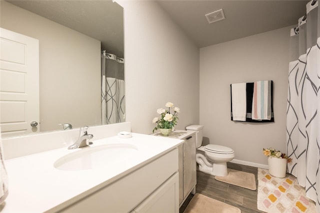 bathroom with toilet, wood finished floors, vanity, visible vents, and baseboards