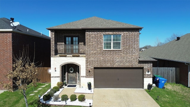 view of front of property featuring a garage, a balcony, and a front lawn