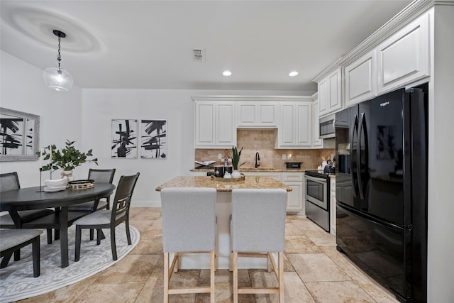 kitchen with decorative backsplash, appliances with stainless steel finishes, decorative light fixtures, and white cabinetry