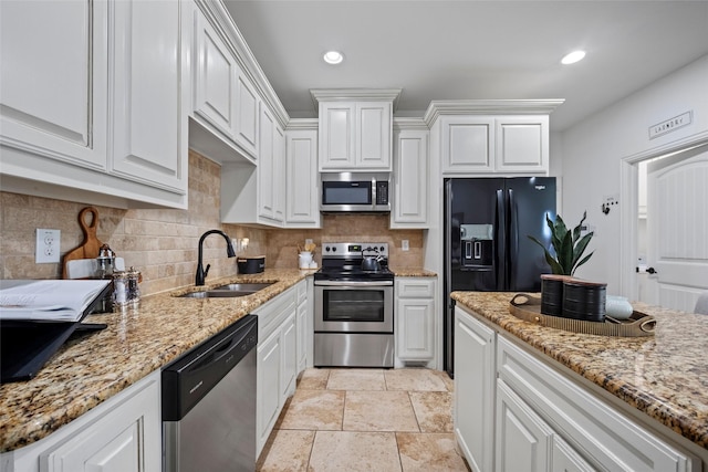 kitchen with appliances with stainless steel finishes, tasteful backsplash, light stone counters, sink, and white cabinets