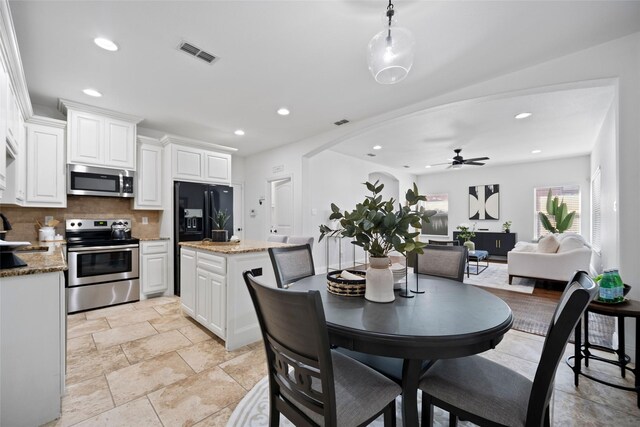 kitchen with light stone countertops, white cabinetry, ceiling fan, stainless steel appliances, and decorative backsplash